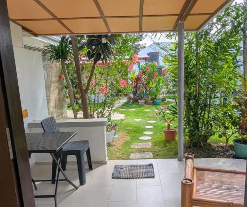 a patio with a table and chairs and a garden at Astillo's Guest Houses in Moalboal