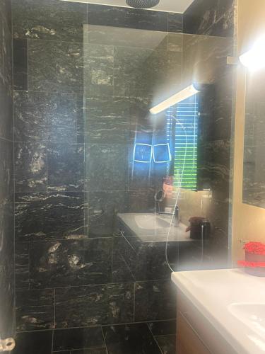 a black tiled bathroom with a sink and a mirror at Boutique glam and chic apartament in Rothrist in Rothrist