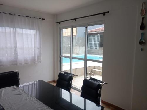 a bedroom with a bed and two chairs and a large window at Hostel da Duda II in Itanhaém