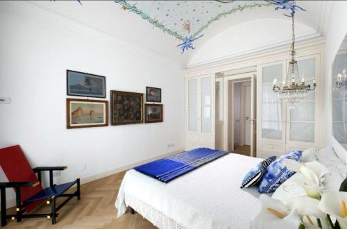 a white bedroom with a bed and a chandelier at Villa Lalen Sorrento Private Luxury Residence with Garden, Terrace & Jacuzzi in Sorrento