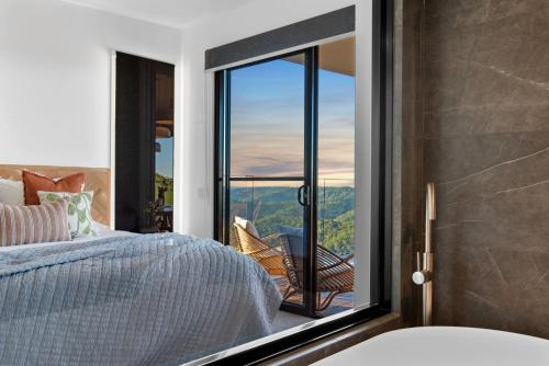 a bedroom with a bed and a large glass window at The Ridge at Maleny Deluxe Residence - Panoramic Valley Views in Maleny