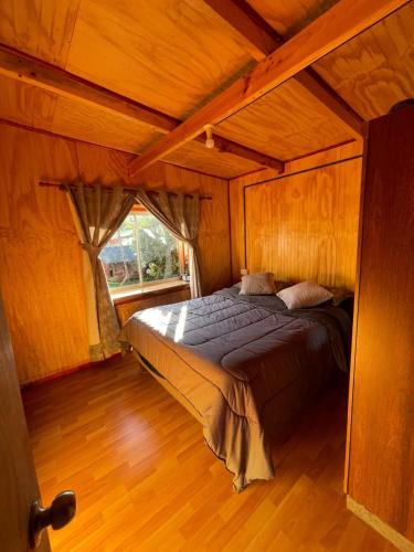 a bedroom with a bed in a wooden room at Cabañas Maite Panguipulli Calafquen 2 in Huellahue