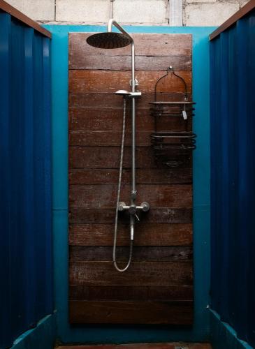a shower in a bathroom with a wooden wall at TT Premium Hostel Vientiane in Vientiane