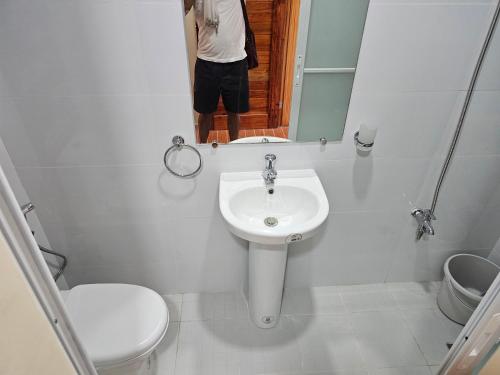 Eine Person fotografiert ein Badezimmer mit Toilette und Waschbecken. in der Unterkunft Kuyang's Place in Bulala