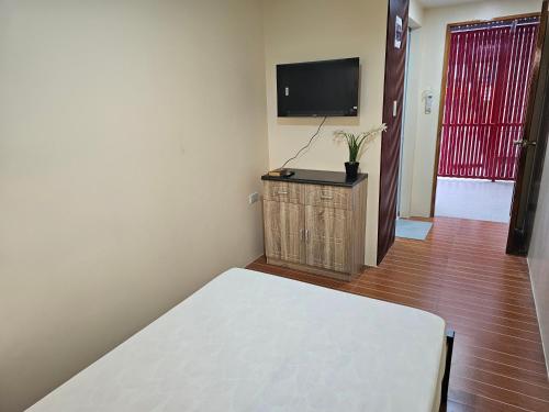 ein Zimmer mit einem Bett und einem Flachbildfernseher in der Unterkunft Kuyang's Place in Bulala