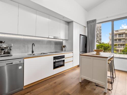 a kitchen with white cabinets and stainless steel appliances at Executive Beachside Getaways in Maroochydore