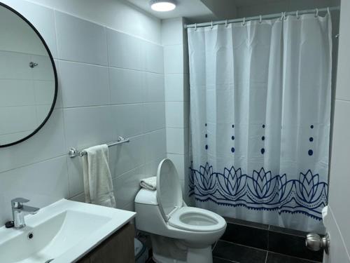 a bathroom with a toilet and a shower curtain at Costanera240 in El Quisco