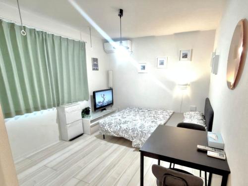 a room with a bed and a desk and a television at ティエラ北池袋 in Tokyo