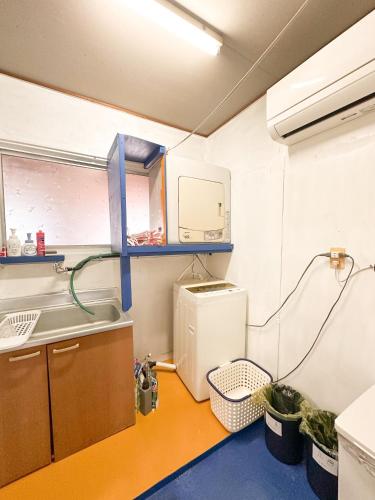 a small kitchen with a sink and a washing machine at ゲストハウスまるとく in Yoron