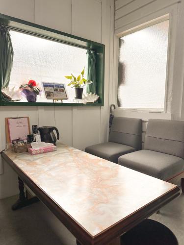 a room with a table and two chairs and a window at ゲストハウスまるとく in Yoron