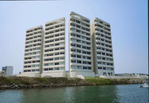 a large white building next to a body of water at Cabo Marino Apartment, Pool, Beach and Marina in Conchal