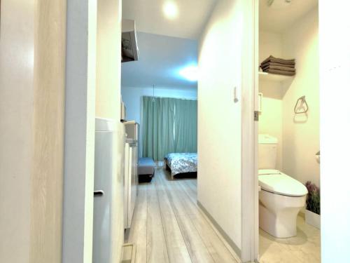 a bathroom with a toilet and a room with a bed at ティエラ北池袋 in Tokyo