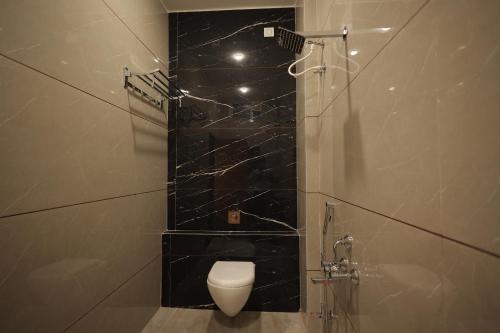 a bathroom with a toilet and a shower with black tiles at The Gravity Inn in Indore
