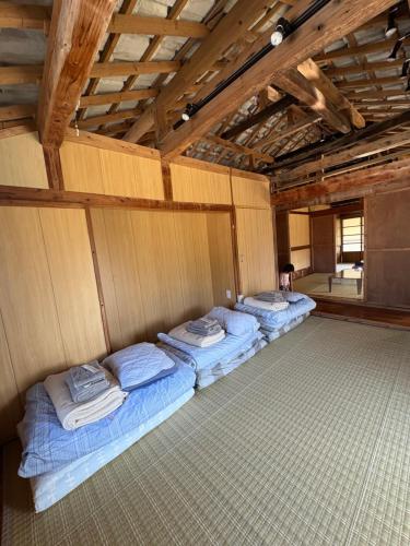 a room with four beds in it with a person sitting in it at Kukaru クカル 伊平屋島の古民家一棟貸し in Gakiya