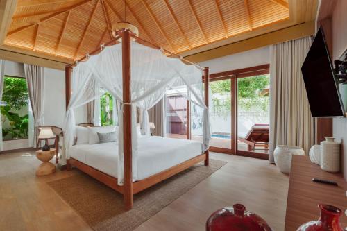 a bedroom with a canopy bed and a television at Metadee Concept Hotel in Kata Beach