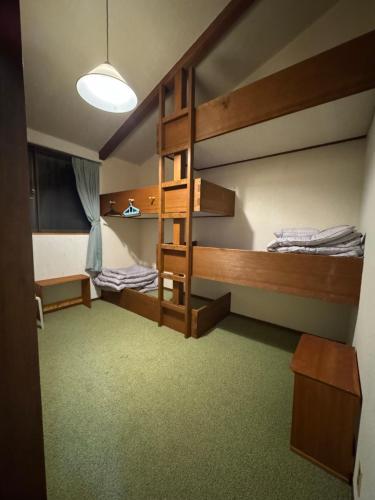 a room with two bunk beds and a lamp at ゲストハウスルスティゲス in Kijimadaira