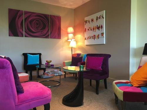 a waiting room with colorful chairs and a table at Lys Hôtel in Halluin