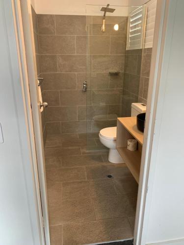 a bathroom with a toilet and a glass shower at Batemans Bay Lodge in Batemans Bay