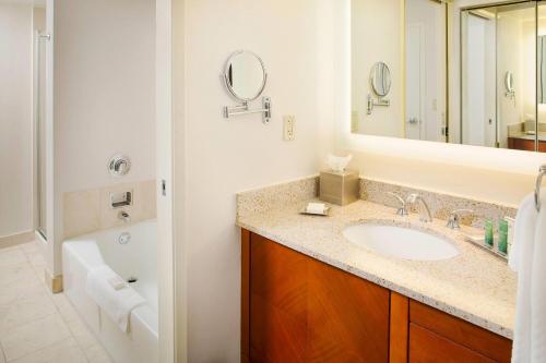 a bathroom with a sink and a tub and a mirror at Wyndham Atlanta Perimeter in Atlanta