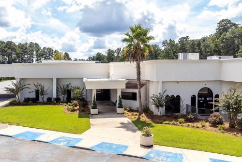a white house with a palm tree in front of it at Cottonwood Suites Savannah Hotel & Conference Center in Pooler