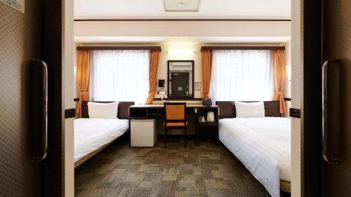 a hotel room with two beds and a desk at Toyoko Inn Fukuyama-eki Shinkansen Minami-guchi in Fukuyama