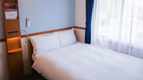 a bed in a room with a window at Toyoko Inn Kagoshima Temmonkan No 1 in Kagoshima