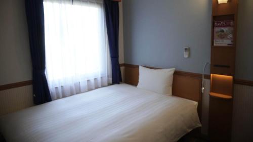 a small bed in a room with a window at Toyoko Inn Kagoshima Temmonkan No 1 in Kagoshima