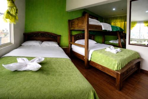 two beds in a room with green walls at Hotel Restaurante El Madroño Chia in Chía