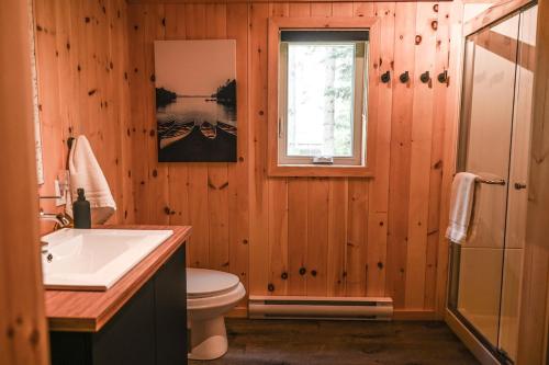 a bathroom with a sink and a toilet and a window at Refuge du Kodiak BORD DE L EAU in Sainte-Germaine-du-Lac-Etchemin