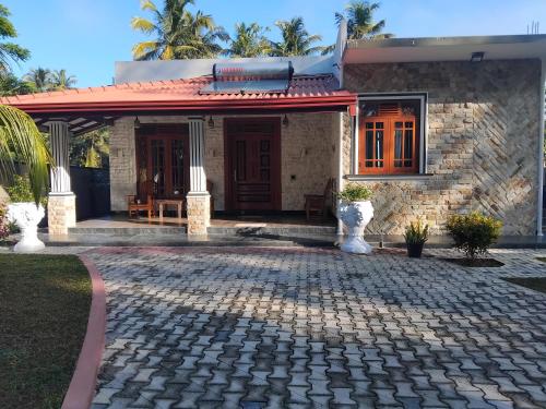 a house with a cobblestone driveway in front of it at SAS Villa in Ahungalla