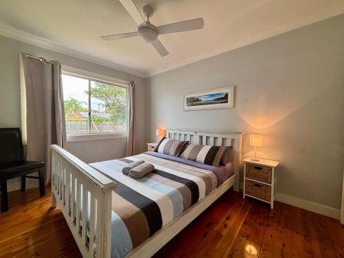 a bedroom with a bed with a ceiling fan at Watts @ Callala Beach-Pet Friendly in Callala Beach