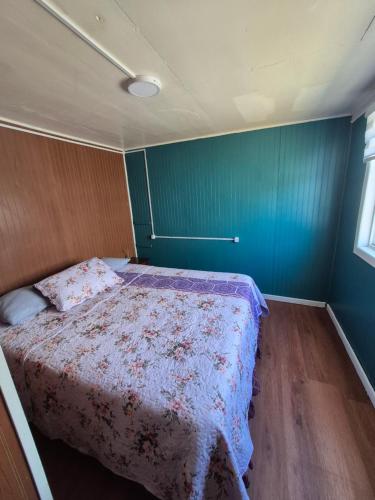 a bedroom with a bed with a floral bedspread at Cabaña ByB in Dalcahue