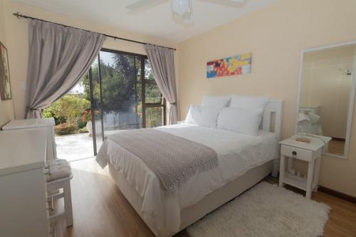 a bedroom with a white bed and a large window at Hartenbos Tranquility in Mossel Bay