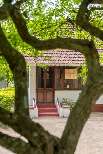 a small building with a red door through a tree at The Anexure - Great Estate Stay for Remote Work in Siddapur