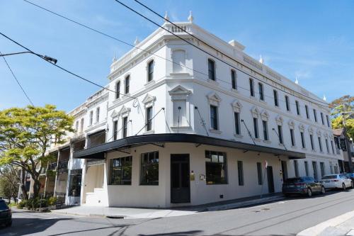 a white building on the corner of a street at The Grand National Hotel by Saint Peter in Sydney