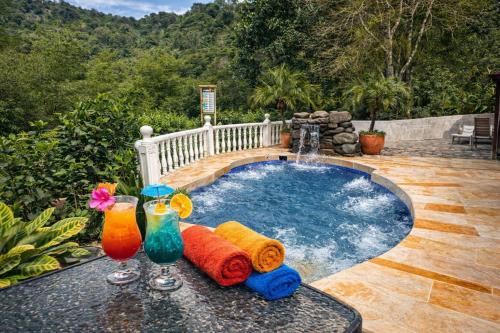 a swimming pool with two drinks on a table at El Remanso del Colibri in La Vega