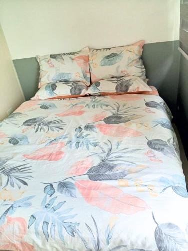 a bed with a floral comforter and two pillows at Haute Haven - 1br with Balcony in Manila