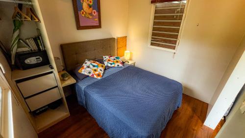 a small bedroom with a bed with blue sheets and pillows at Tiny house with pool near Vaiava beach in Punaauia