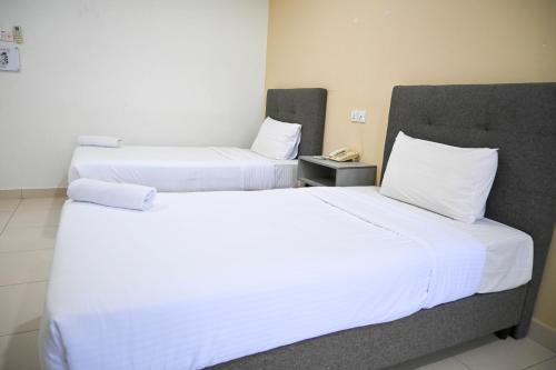 two beds in a hotel room with white sheets and pillows at Pusat Belia Antarabangsa in Kuala Lumpur