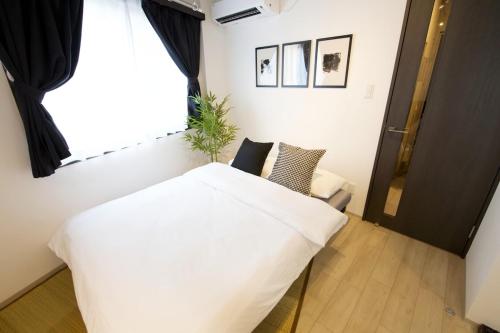 a bedroom with a large white bed and a window at FelizLife 南馬込 201 in Tokyo