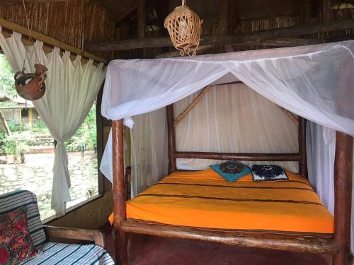 a bed in a room with a canopy at Ecolodge Rancho del Lago in Santomé