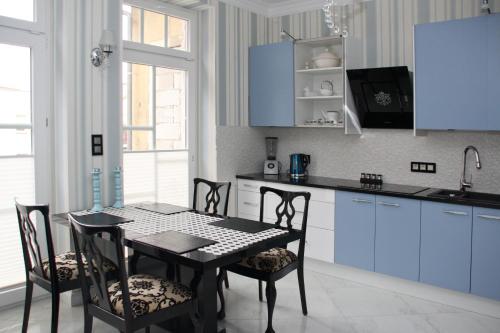 a kitchen with blue cabinets and a table and chairs at Apartamenty Boutique in Ustka