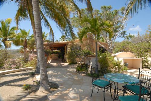 a patio with a table and chairs and palm trees at La Valise Los Cabos in Boca de la Vinorama
