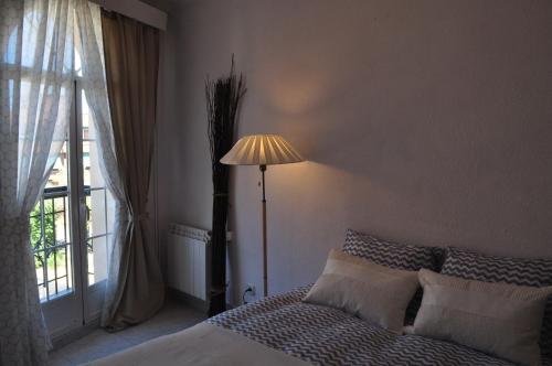 1 dormitorio con 1 cama con lámpara y ventana en Cuatro Camino Apartment with elevator, en Madrid