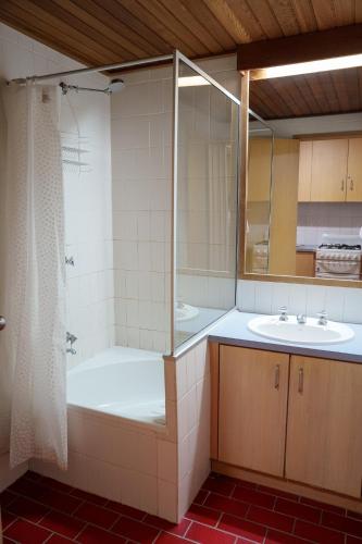 a bathroom with a shower and a tub and a sink at Arlberg Hotham in Mount Hotham