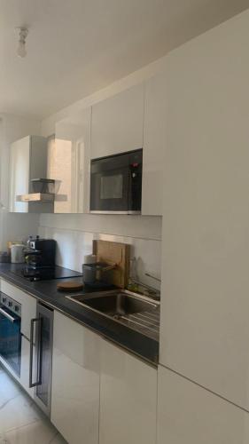 une cuisine avec un évier et un micro-ondes dans l'établissement suresnes centre, à Suresnes
