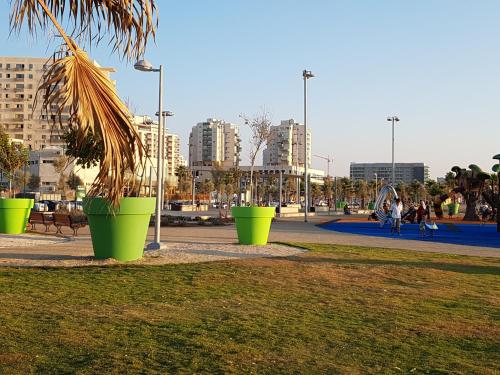 a park with green potted plants in a city at Spat Hotel Ashdod in Ashdod