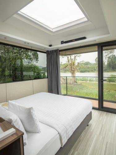 a bedroom with a large bed and a large window at Mont Du Kwai Resort in Ban Yang (2)