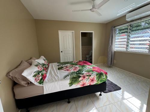 a bedroom with a bed with a floral comforter at Secure Vailima Home with Fale in Apia