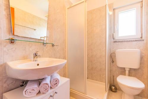 a bathroom with a sink and a toilet and a shower at Apartments Alba in Fažana